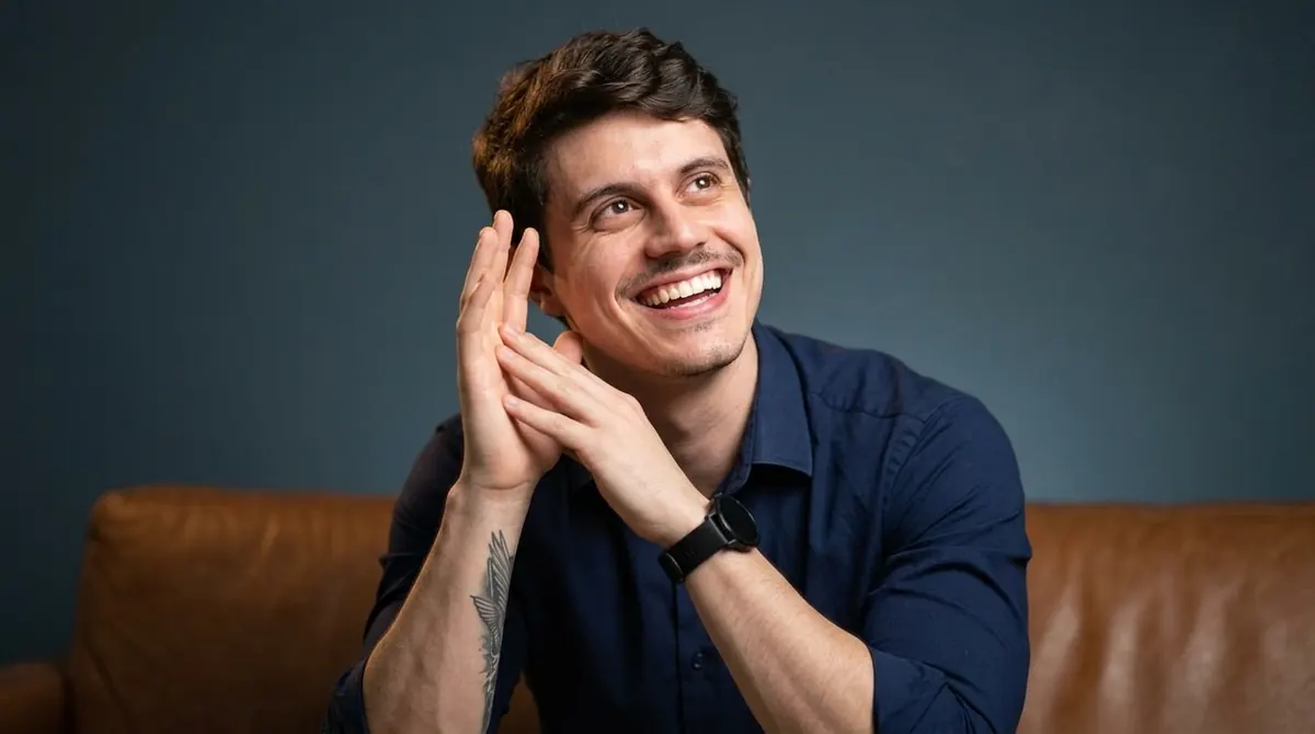 João Chimelli sorrindo, sentado em um sofá
