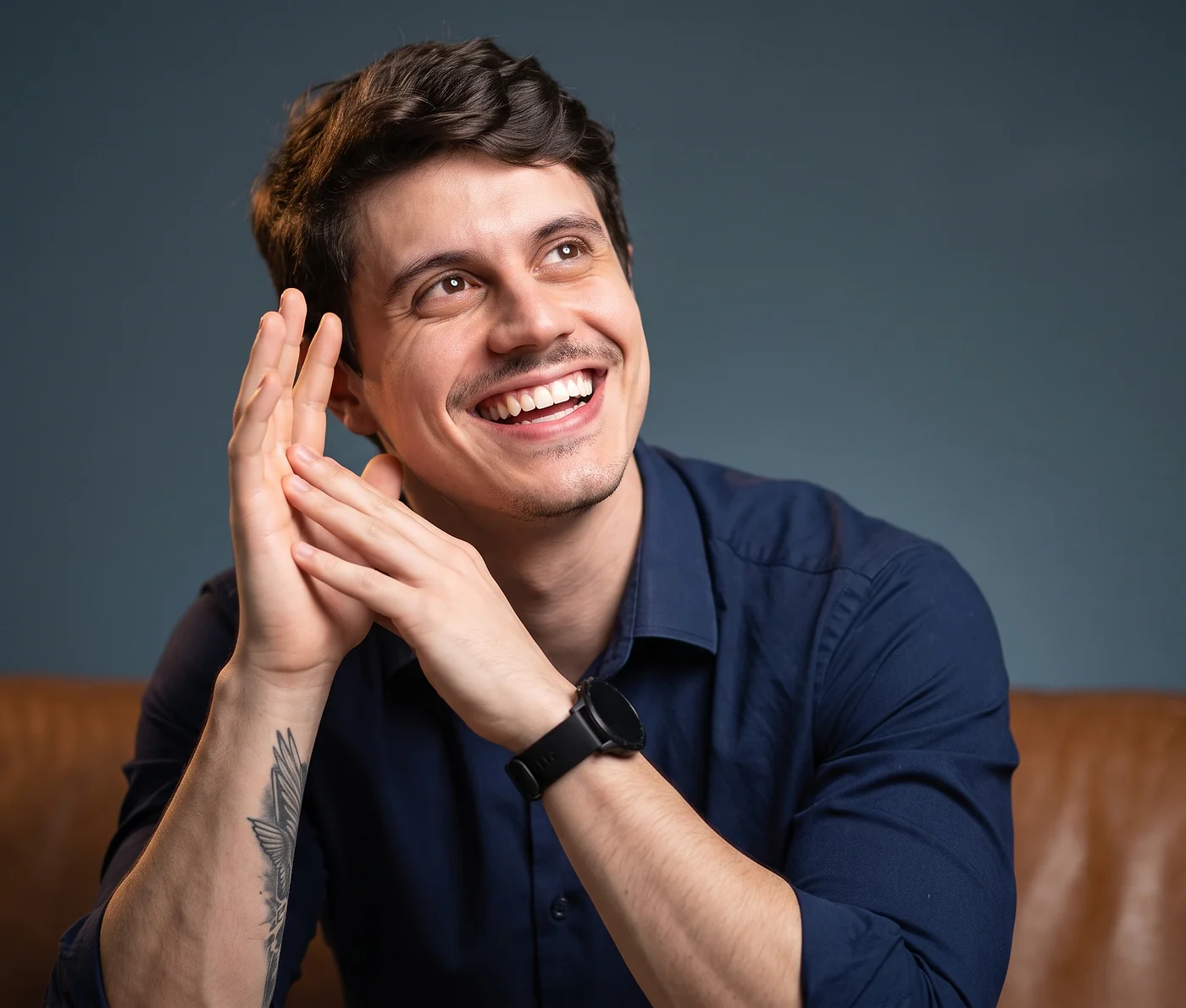 João Chimelli sorrindo, sentado em um sofá